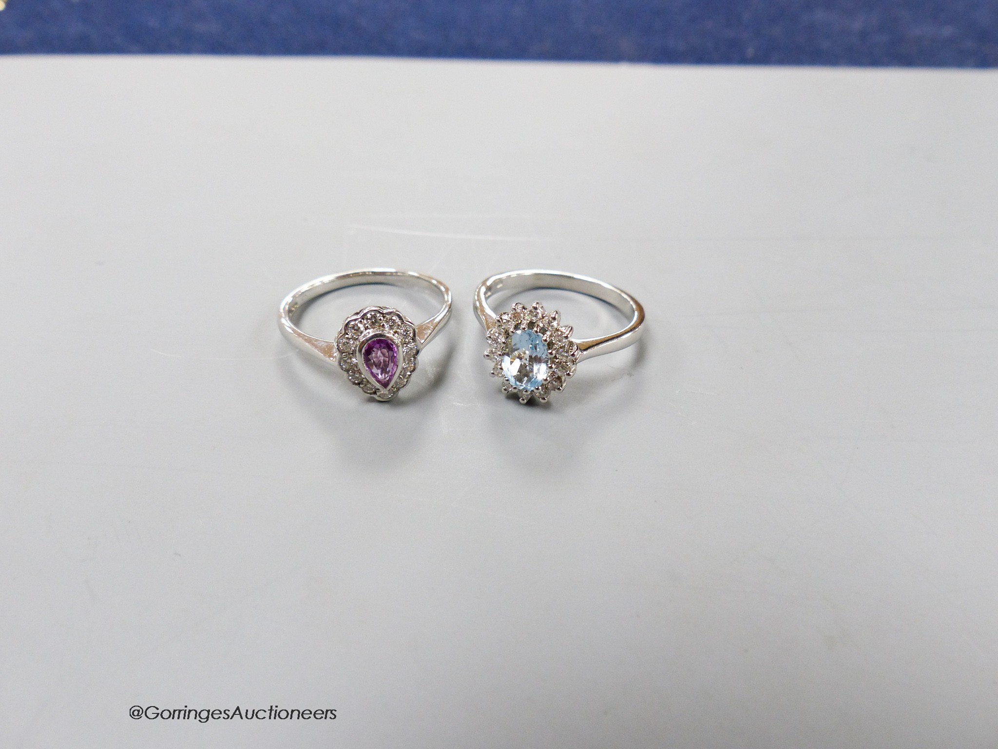 A modern 9ct white gold, pink sapphire and diamond cluster ring, size O and a similar blue topaz and diamond cluster ring, size N/O, gross 6.1 grams.